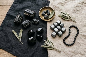 Flat-lay kamieni ochronnych: czarny turmalin, obsydian, hematyt i onyks na ciemnym lnie
