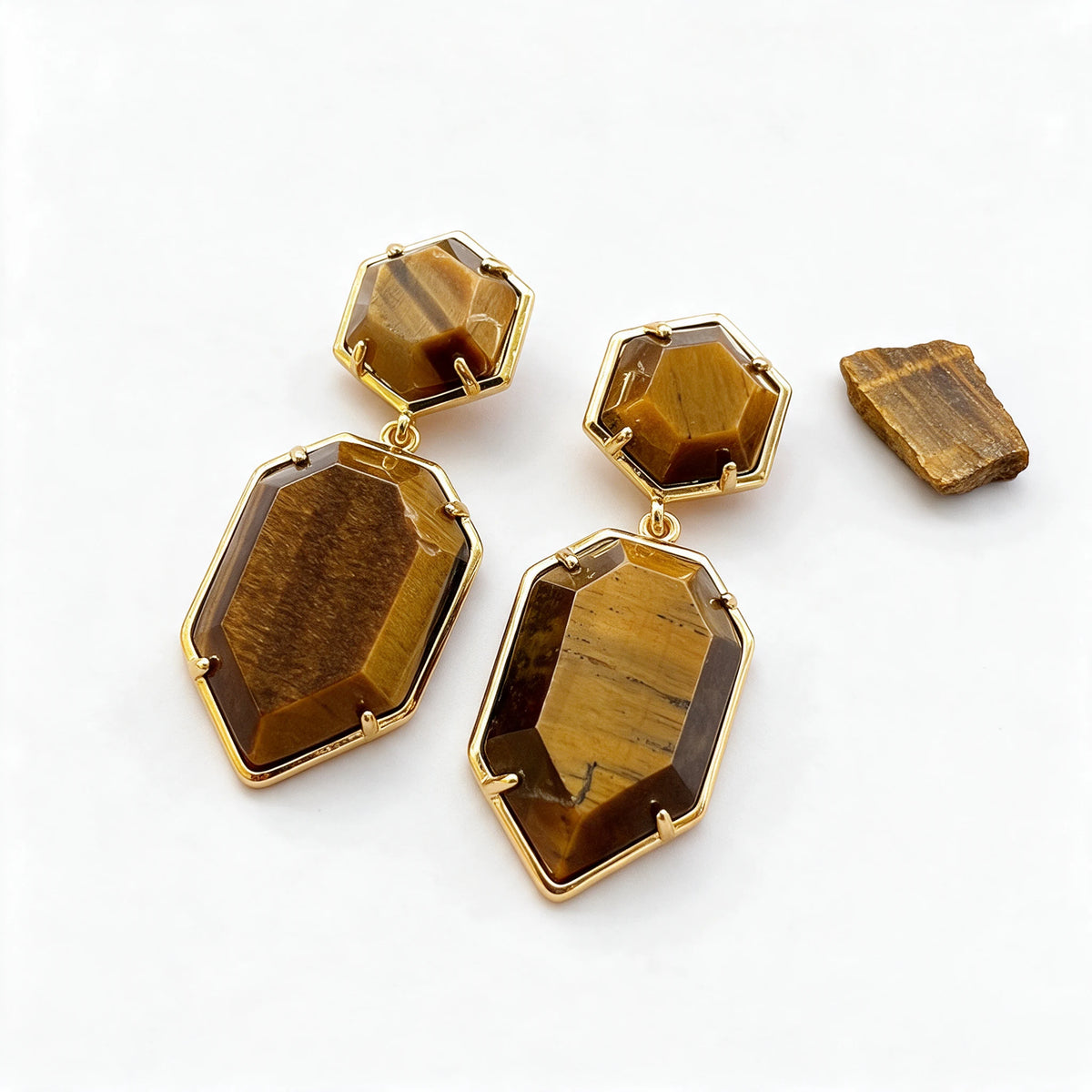 Kolczyki Spica z tygrysim okiem obok surowego tygrysiego oka, minerał poza zestawem